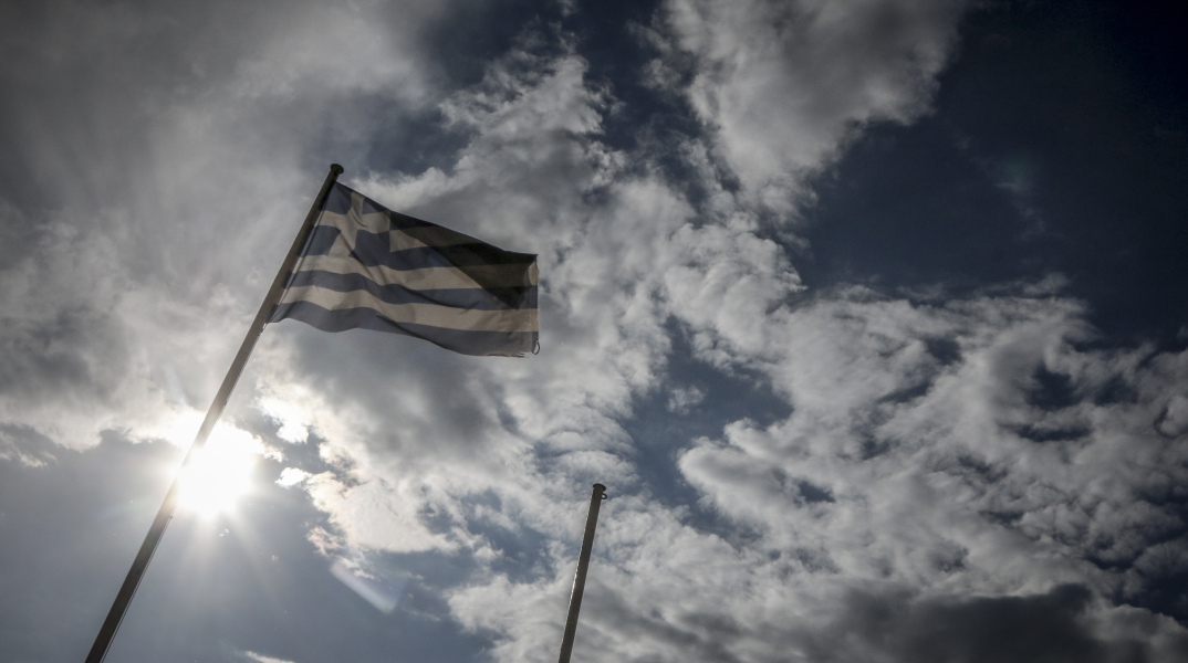 Σύννεφα πίσω από ελληνική σημαία