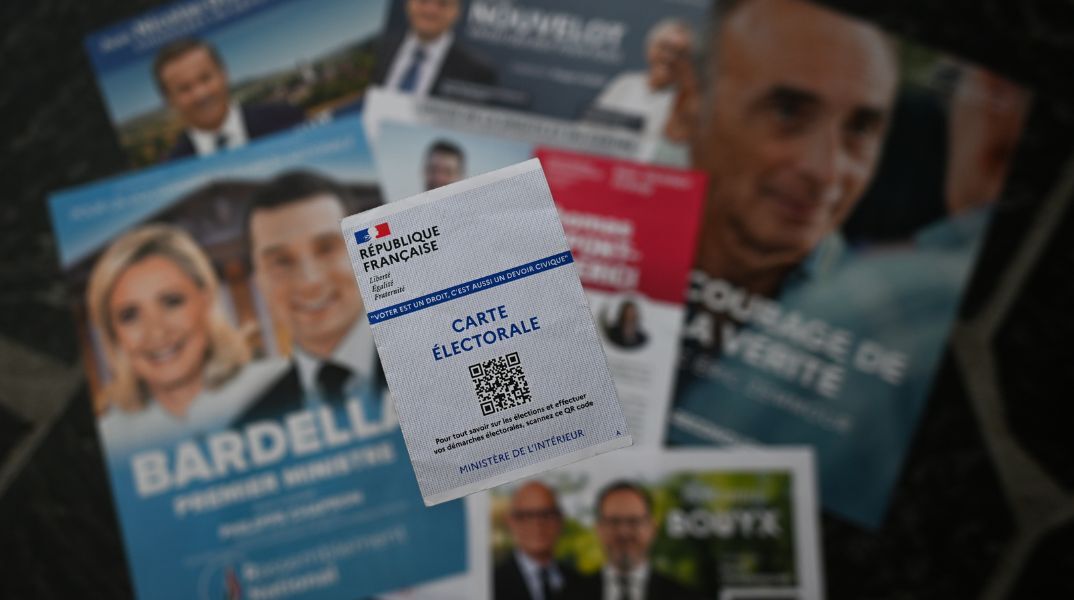 Κάρτα για την άσκηση του εκλογικού δικαιώματος στη Γαλλία με φόντο τα φυλλάδια των υποψηφίων