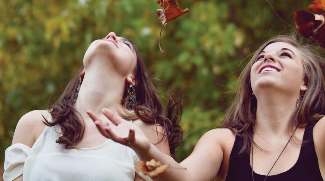 Κορίτσια παίζουν με πεσμένα φύλλα