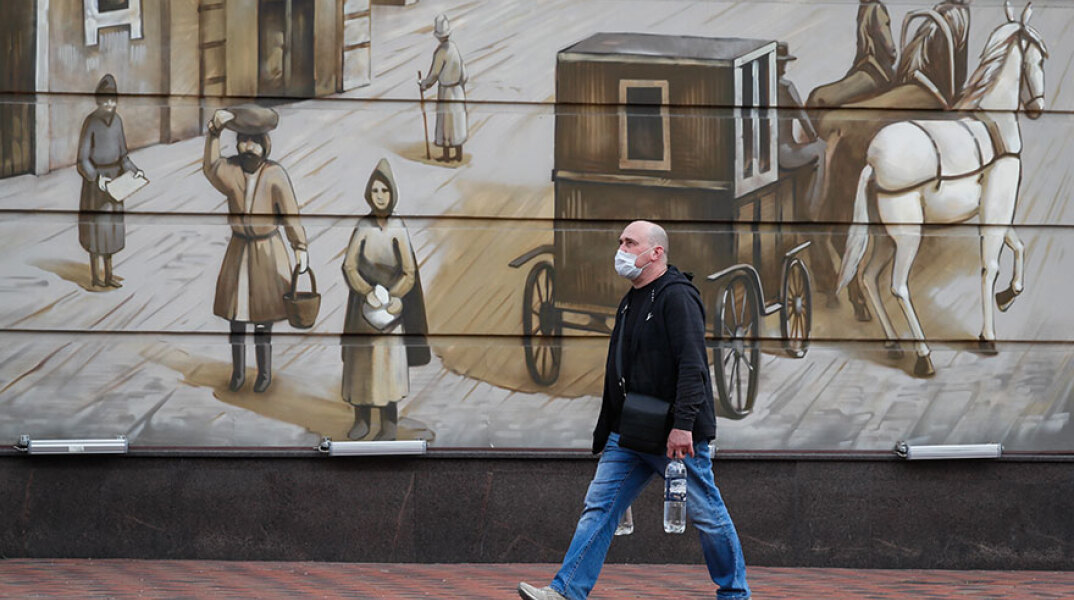 Κορωνοϊός στη Ρωσία: Άνδρας με προστατευτική μάσκα περνά μπροστά από γκράφιτι σε δρόμο της Μόσχας