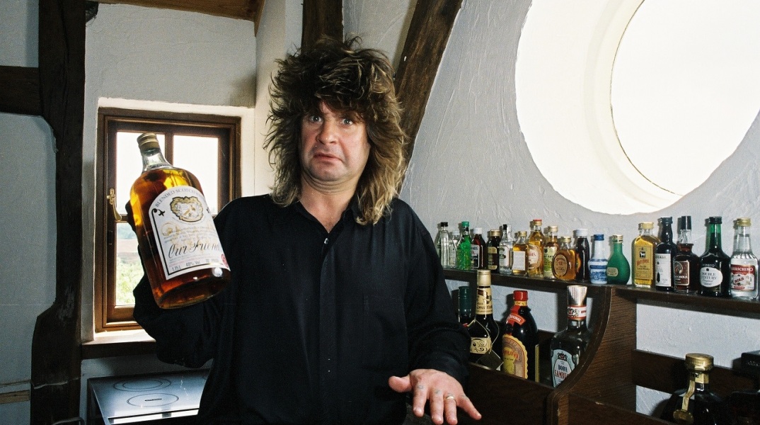Ο Ozzy Osbourne στο σπίτι του κρατά ένα μπουκάλι ουίσκι