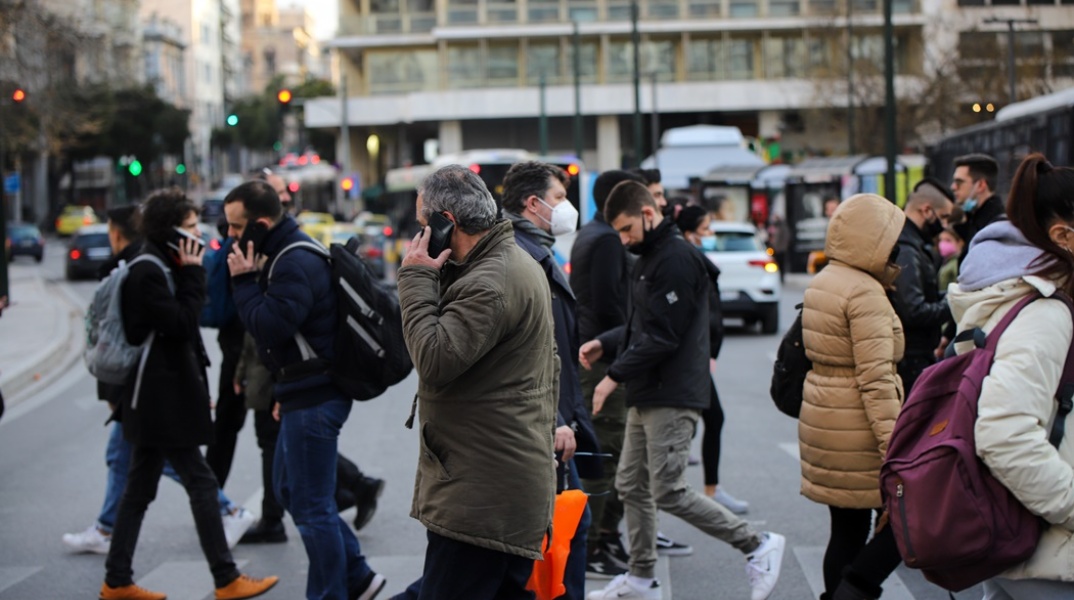 Πολίτες με μάσκα προστασίας από τον κορωνοϊό περπατούν στο κέντρο της Αθήνας