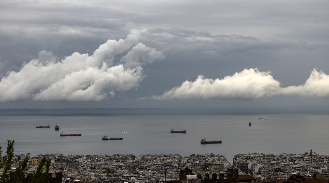 Συννεφιά σε σκοτεινό ουρανό λόγω της κακοκαιρίας πάνω από τη θάλασσα όπου πλέουν εμπορικά πλοία