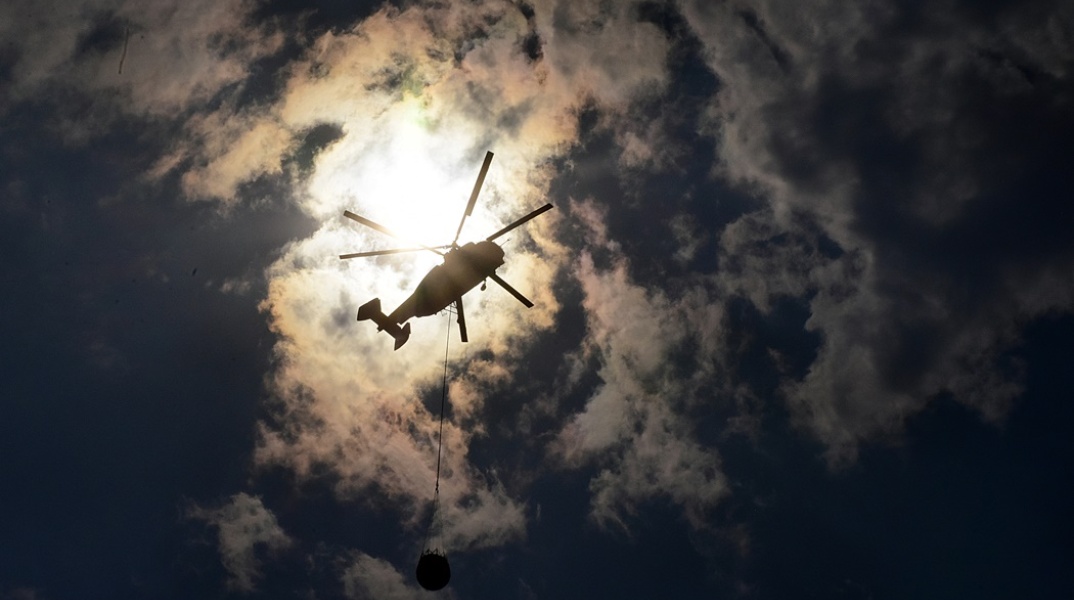 Πυροσβεστικό ελικόπτερο σε λήψη από κάτω με φόντο τα σύννεφα