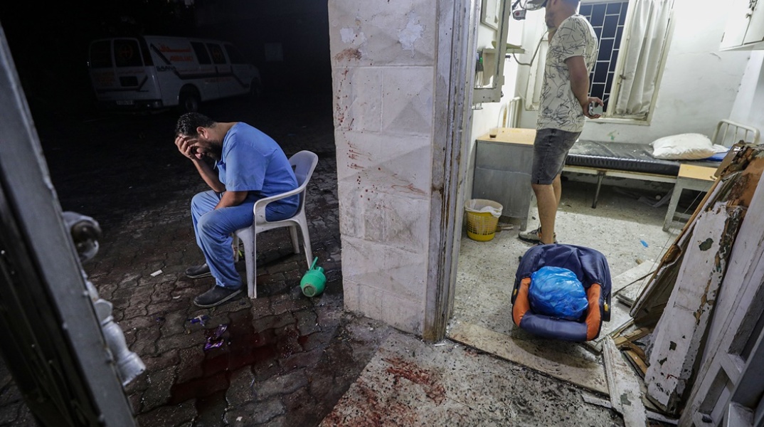 Γιατρός απελπισμένος με τα χέρια στο πρόσωπο σε χώρο δίπλα από το νοσοκομείο της Γάζας - Κηλίδες με αίματα δίπλα του 