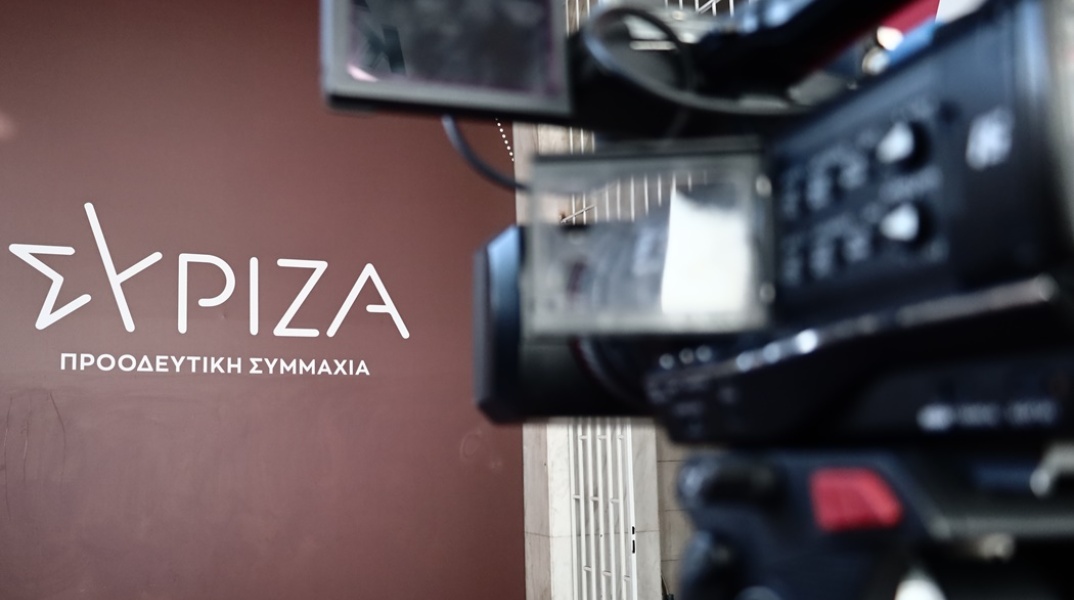 Το λογότυπο του ΣΥΡΙΖΑ και δίπλα κάμερα τηλεοπτικού συνεργείου