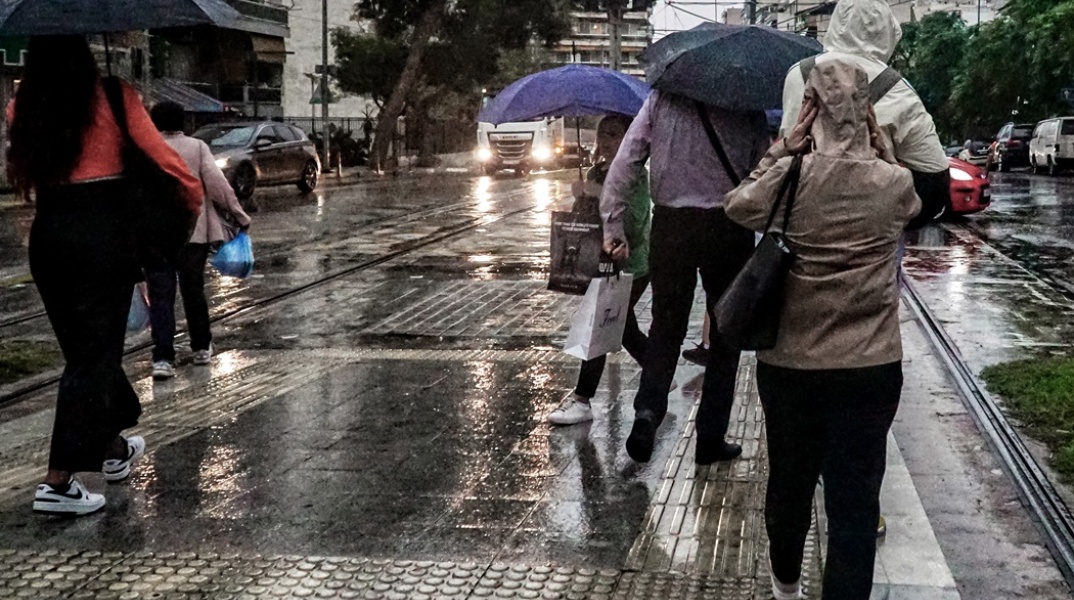Πολίτες με ομπρέλες εν μέσω βροχής