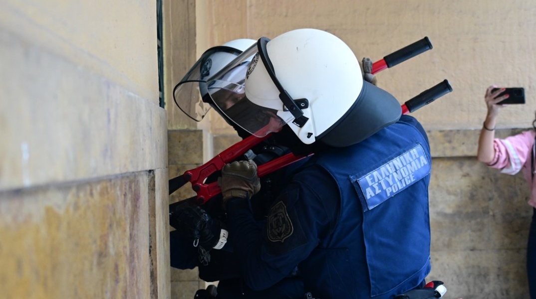 Αστυνομικοί με κόφτη στα χέρια επιχειρούν να κόψουν την αλυσίδα σε πύλη της Νομικής Σχολής Αθηνών