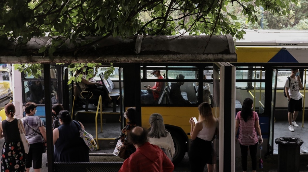 Επιβάτες αναμένουν σε στάση όσο μπροστά τους βρίσκεται λεωφορείο με ανοιχτές τις πόρτες του