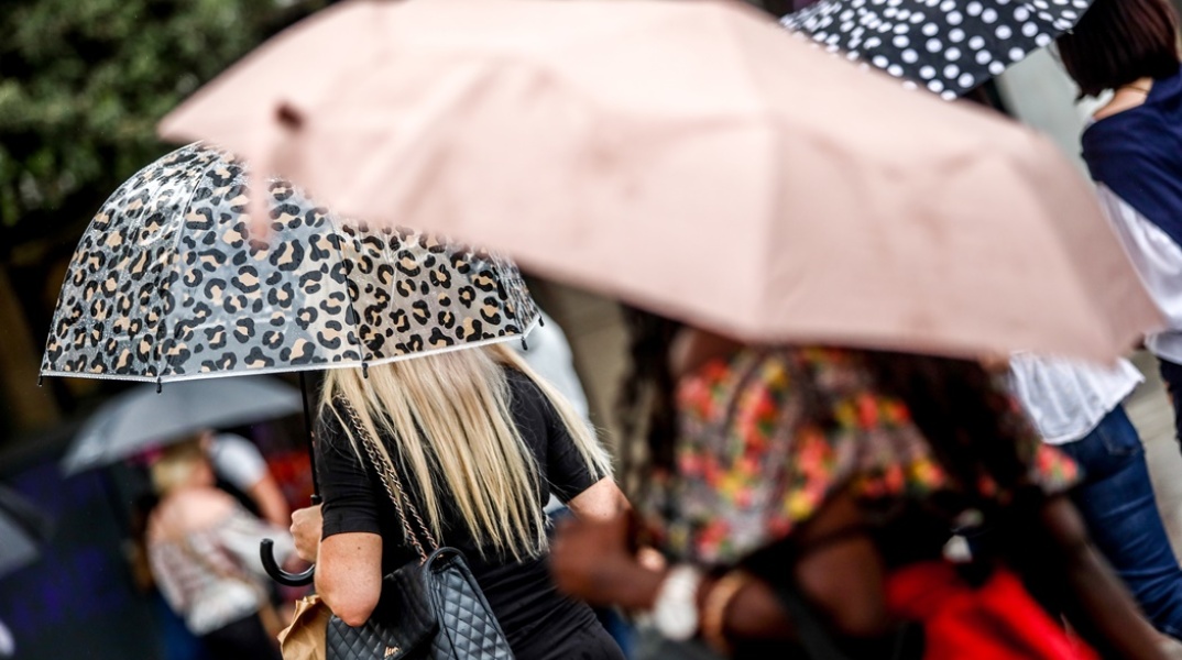 Πολίτες με ομπρέλα προστατεύονται από τη βροχή