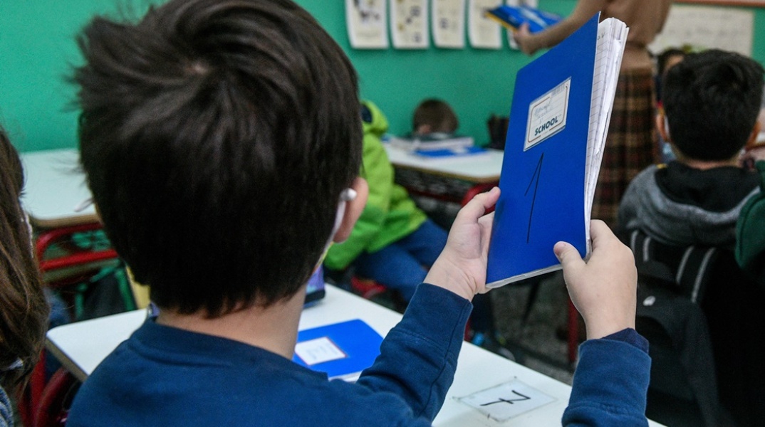 Παιδί με το μπλε τετράδιό του ανά χείρας στην τάξη του