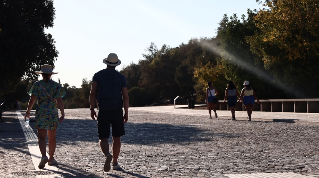 Πολίτες με καπέλο περπατούν στη Διονυσίου Αρεοπαγίτου υπό υψηλές θερμοκρασίες