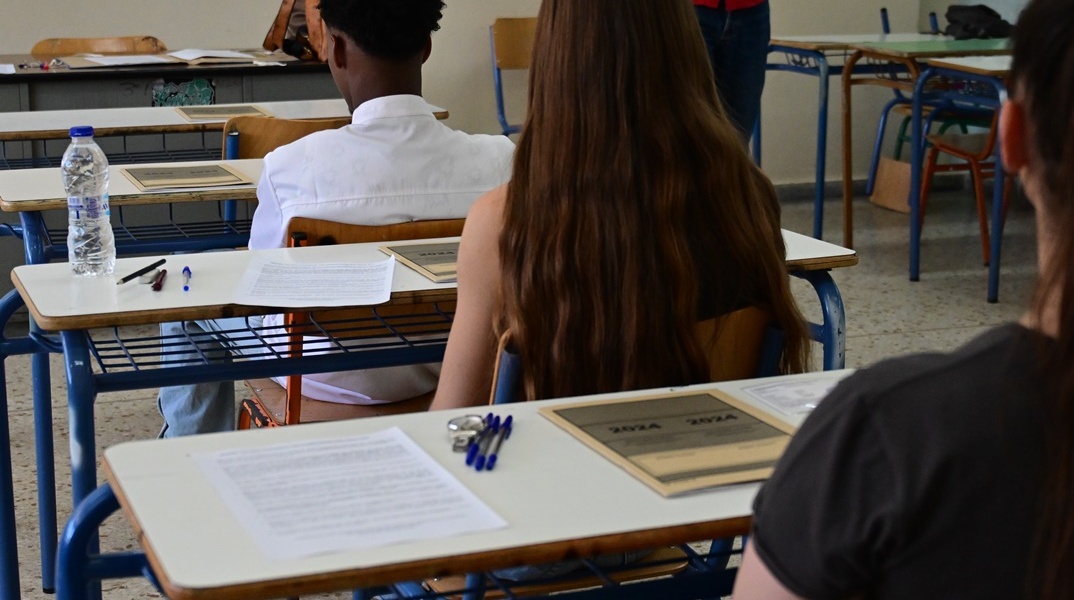 Μαθητές καθισμένοι στις καρέκλες τους μέσα στο εξεταστικό κέντρο, έχουν μπροστά τους το τετράδιο απαντήσεων των Πανελληνίων 2024