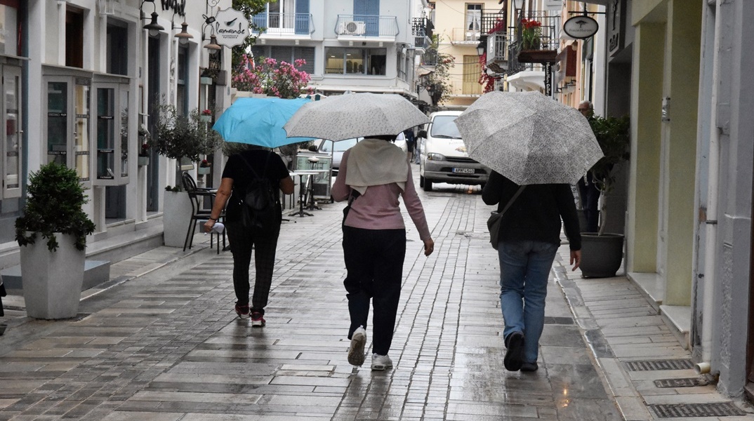 Άτομα κρατούν ομπρέλα ενώ περπατούν στον δρόμο