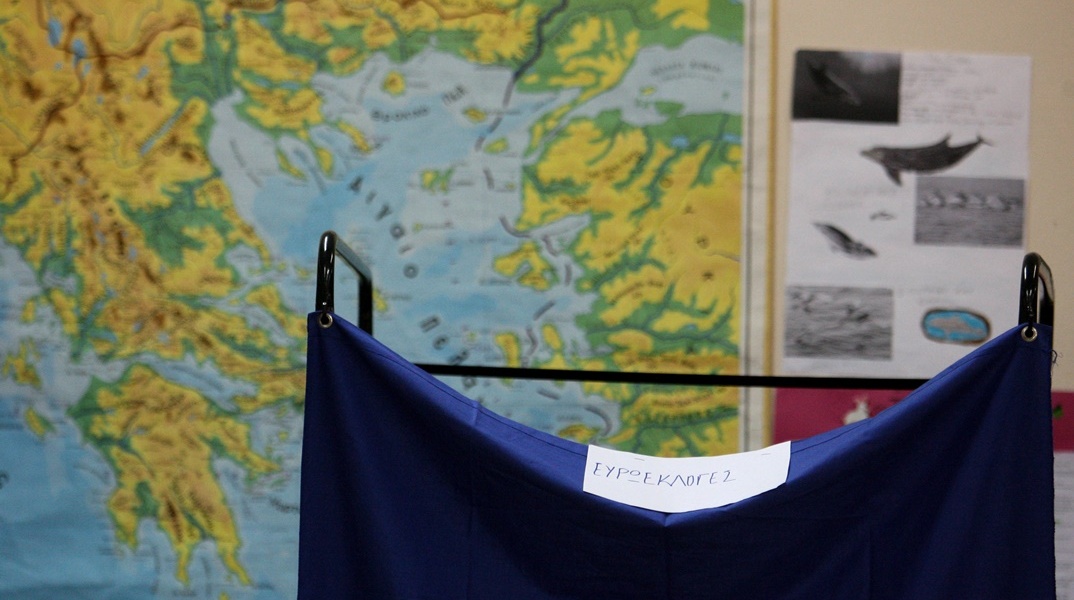 Παραβάν σε εκλογικό τμήμα με φόντο χάρτη της Ελλάδας