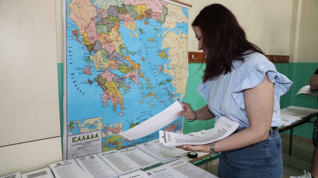 Γυναίκα συλλέγει ψηφοδέλτια σε εκλογικό τμήμα