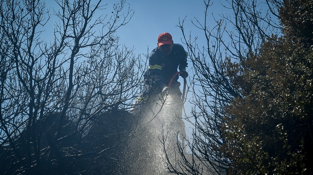 Πυροσβέστης με μάνικα κατά τη διάρκεια κατάσβεσης φωτιάς 