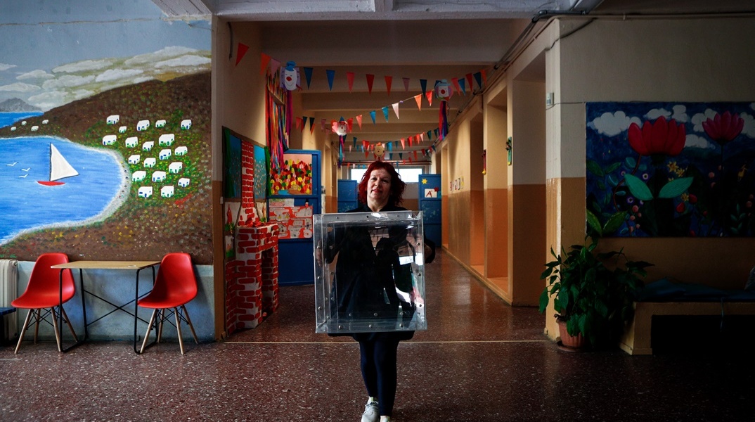 Γυναίκα με κάλπη στα χέρια σε διάδρομο σχολείου