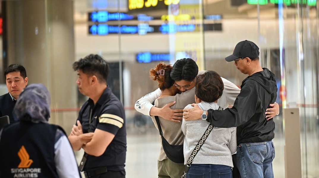 Επιβάτες αγκαλιάζονται με τους συγγενείς τους μετά τις αναταράξεις στο αεροσκάφος της Singapore Airlines