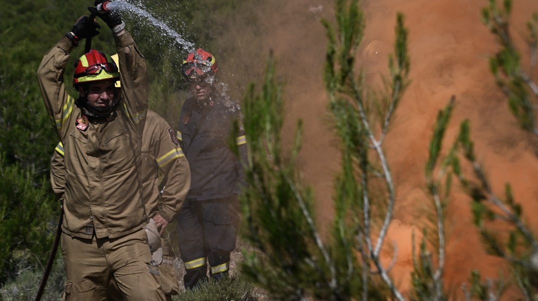 Πυροσβέστης με μάνικα κατά τη διάρκεια κατάσβεσης φωτιάς