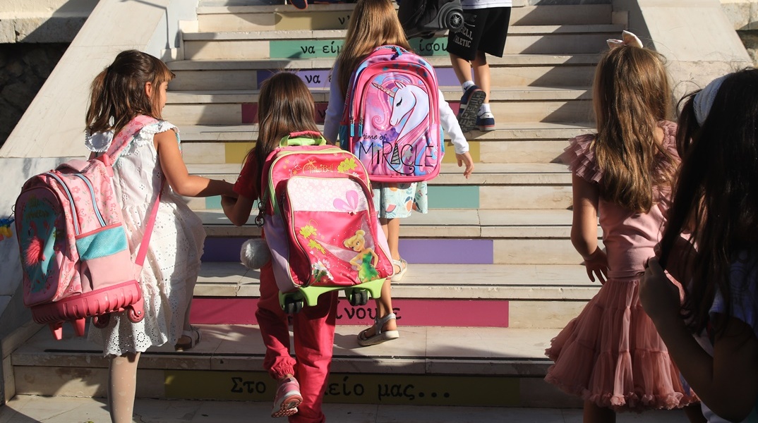 Μαθητές με τις τσάντες τους στην πλάτη ανεβαίνουν τα σκαλιά για να μπουν στο σχολείο τους