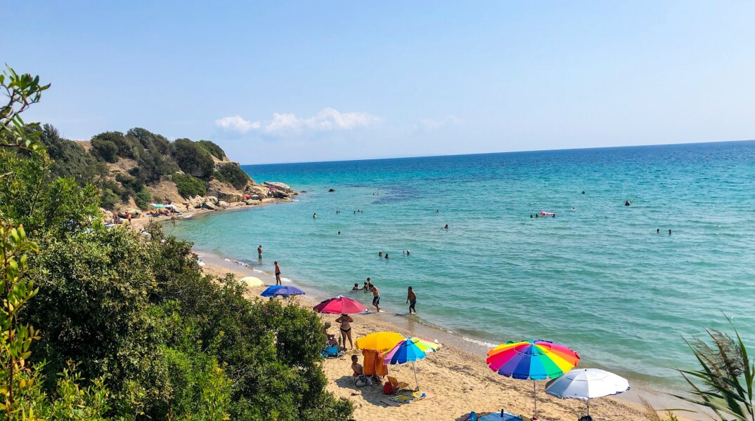 Παραλία στην Ελλάδα και λουόμενοι που απολαμβάνουν το μπάνιο τους
