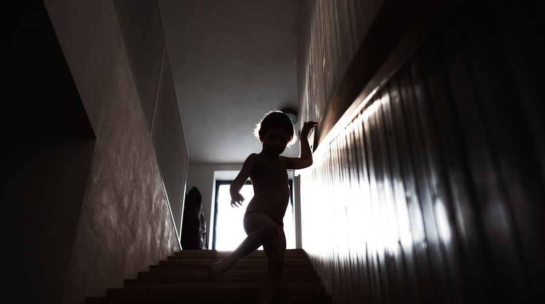 Παιδί κατεβαίνει σκάλες - Φωτογραφία με σκοτεινό φόντο