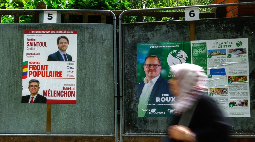 Πολίτες μπροστά από αφίσες εκλογών στη Γαλλία