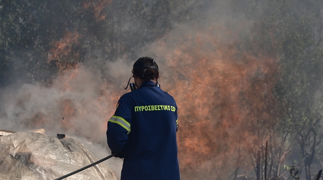 Πυροσβέστης με πλάτη στον φωτογραφικό φακό κατά τη διάρκεια κατάσβεσης φωτιάς