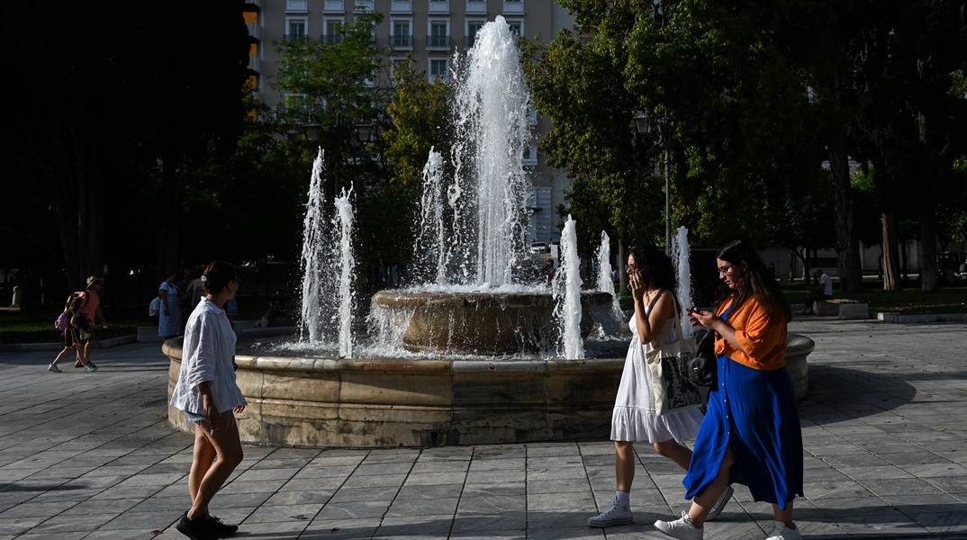 Πολίτες περπατούν στο κέντρο της Αθήνας εν μέσω καύσωνα