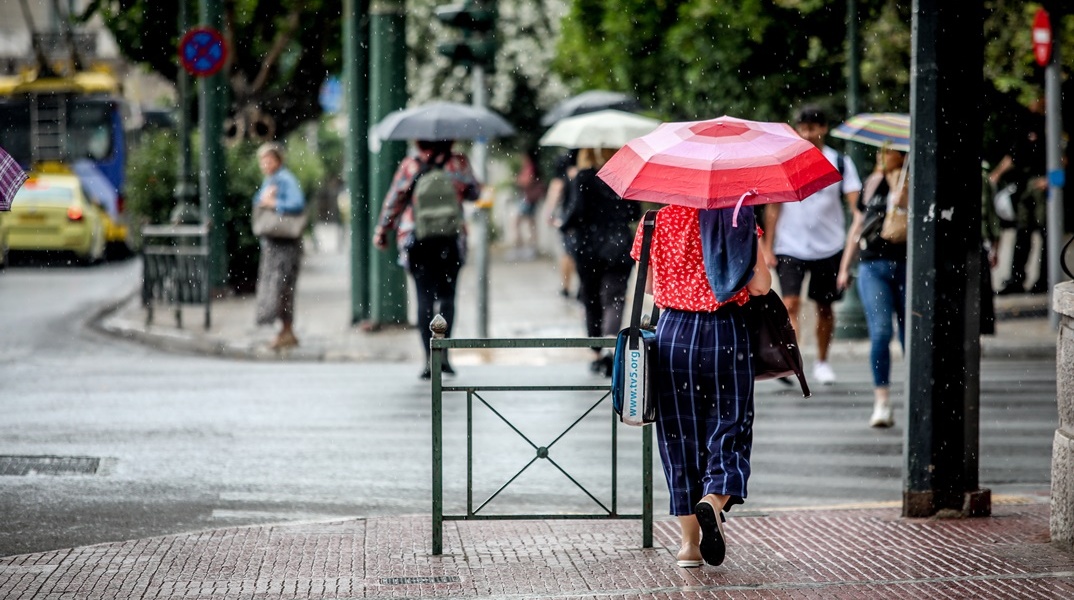 Γυναίκα με ομπρέλα περπατά εν μέσω βροχής