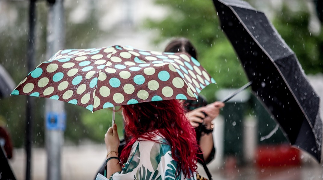 Πολίτες με ομπρέλα εν μέσω βροχής στο κέντρο της Αθήνας