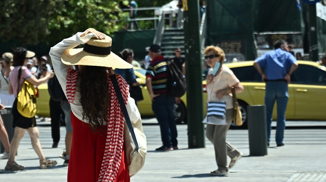 Πολίτες περπατούν στο κέντρο της Αθήνας ενόψει καύσωνα
