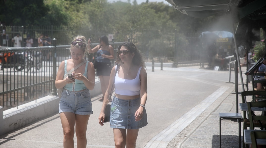 Γυναίκες στο κέντρο της Αθήνας παιρνούν από spot δροσιάς καταστήματος εστίασης