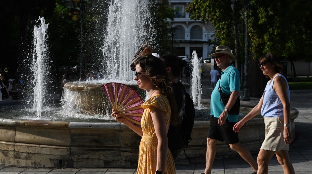 Γυναίκα περπατά στο κέντρο της Αθήνας κρατώντας τη βεντάλια της
