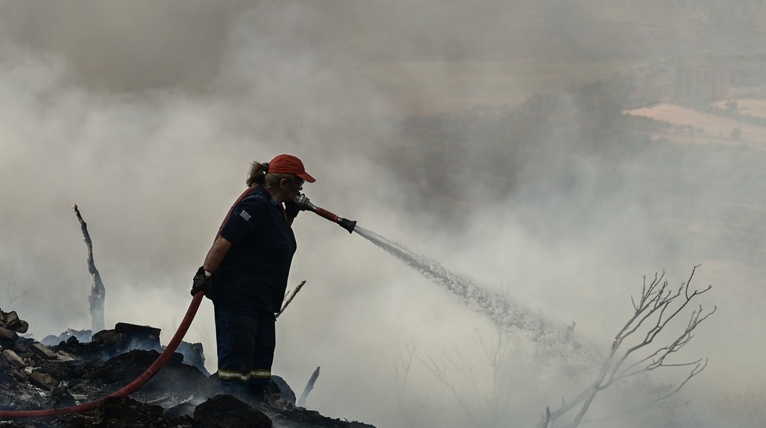 Γυναίκα πυροσβέστης επιχειρεί με τη μάνικα για την κατάσβεση φωτιάς