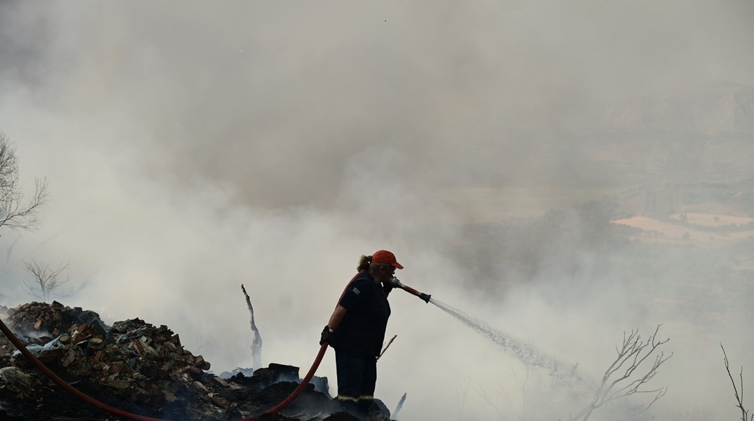 Γυναίκα πυροσβέστης επιχειρεί με τη μάνικα για την κατάσβεση φωτιάς