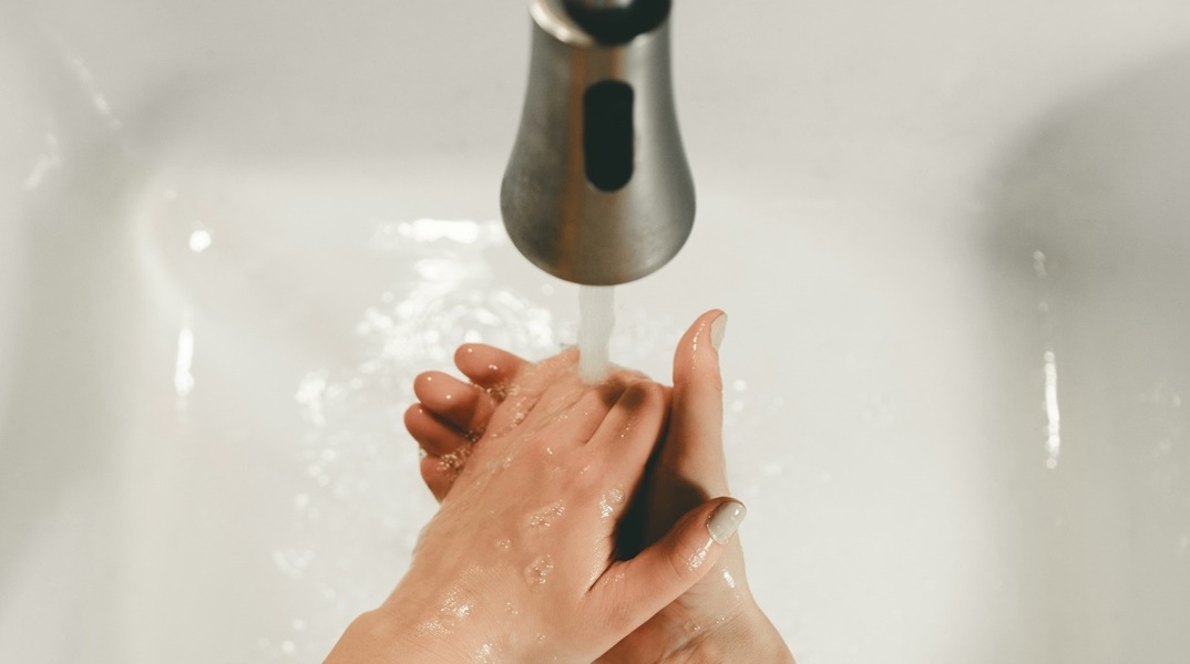 Γυναίκα πλένει τα χέρια της κάτω από τη βρύση
