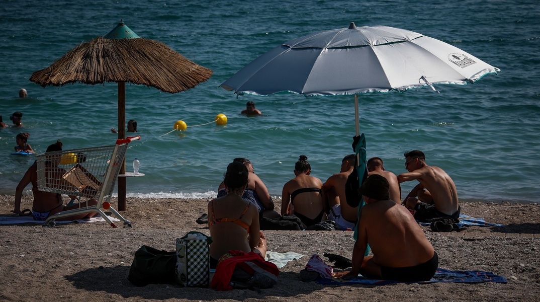 Πολίτες σε παραλία κάτω από ομπρέλα για λίγες στιγμές δροσιάς