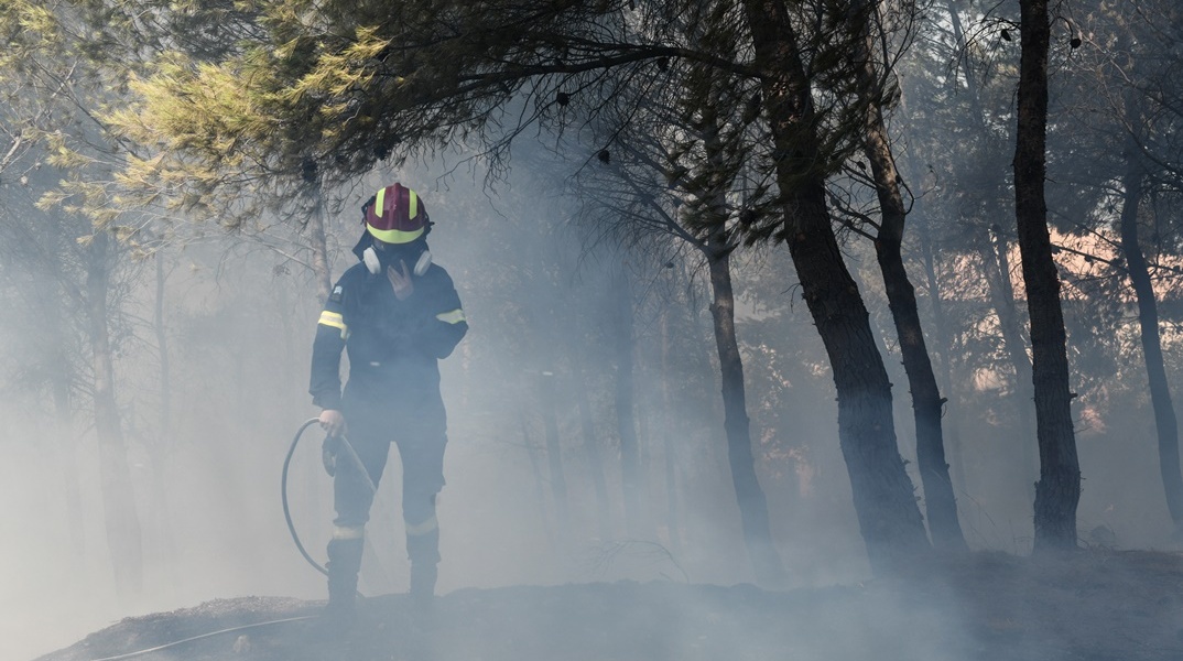 Πυροσβέστης με μάνικα επιχειρεί για την κατάσβεση φωτιάς