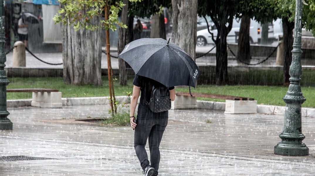 Άτομο προστατεύεται με ομπρέλα από καταιγίδα