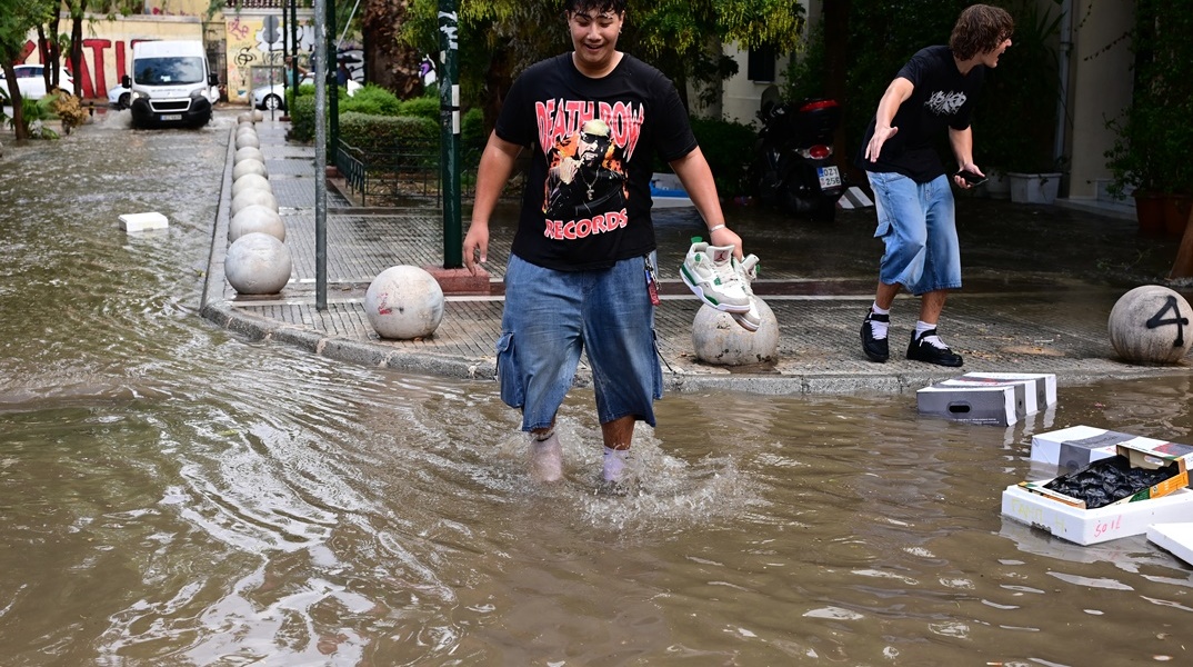 Πολίτης περπατά σε πλημμυρισμένο δρόμο της Αττικής μετά από την ισχυρή καταιγίδα που έφερε η κακοκαιρία Atena