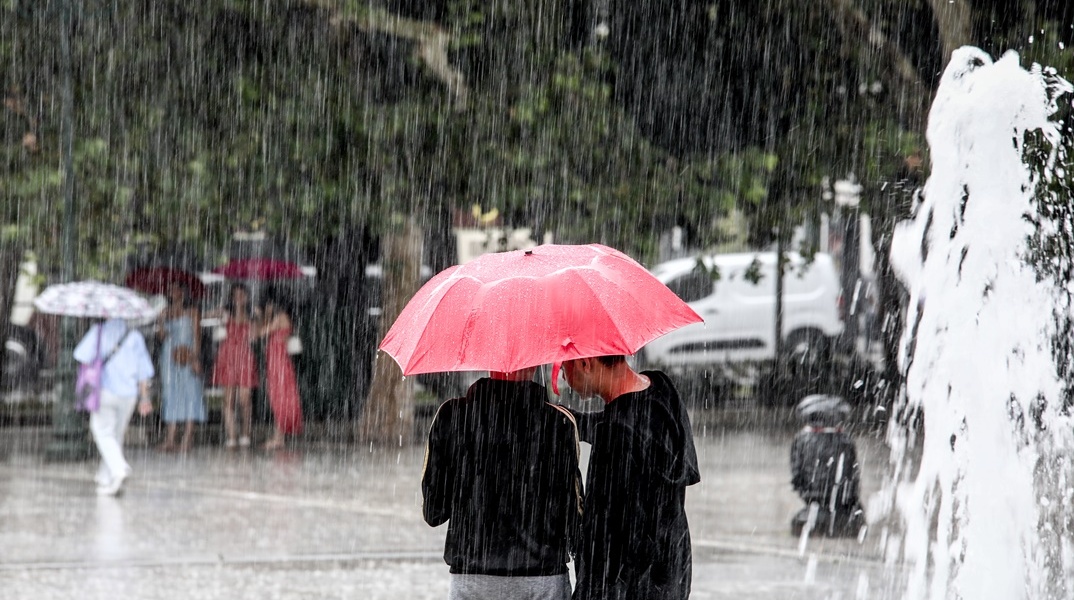 Πολίτες με ομπρέλα προστατεύονται από τη βροχή