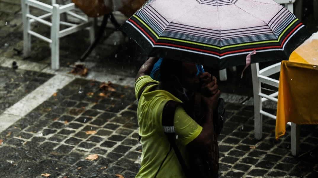 Πολίτες με ομπρέλες προστατεύονται από τη βροχή