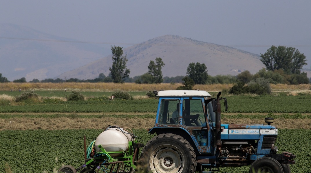 Αγρότης με τρακτέρ σε χωράφι