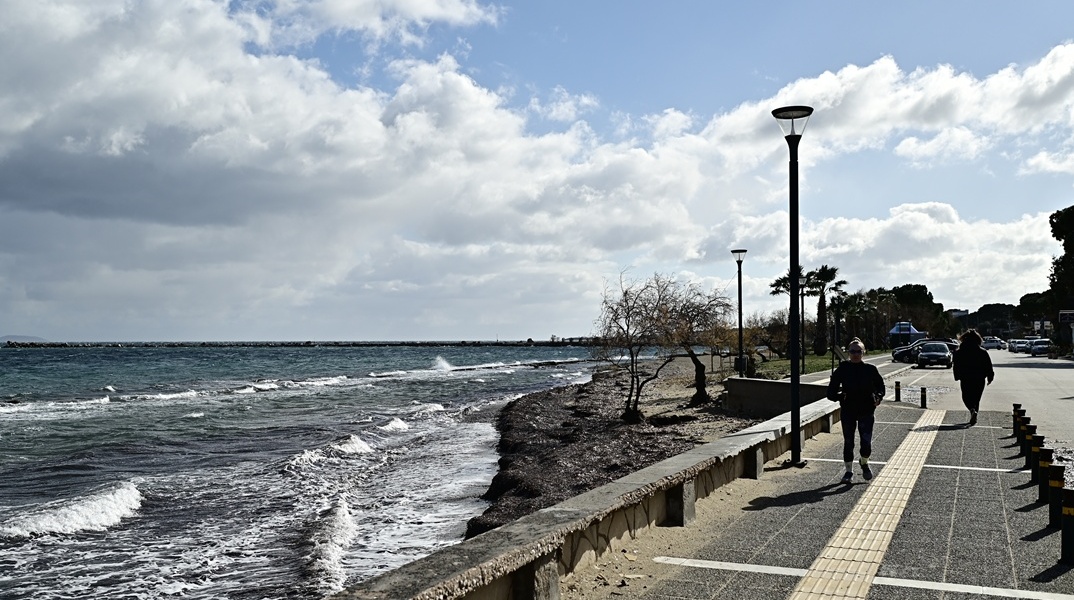 Άτομα που περπατούν δίπλα στην αγριεμένη θάλασσα