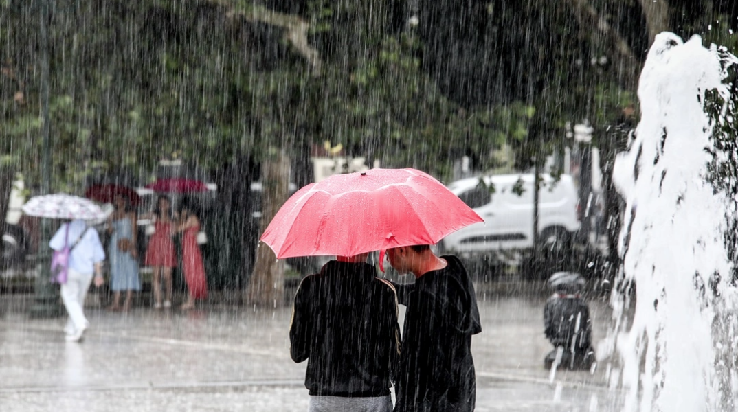 Πολίτες με ομπρέλες προστατεύονται από τη βροχή