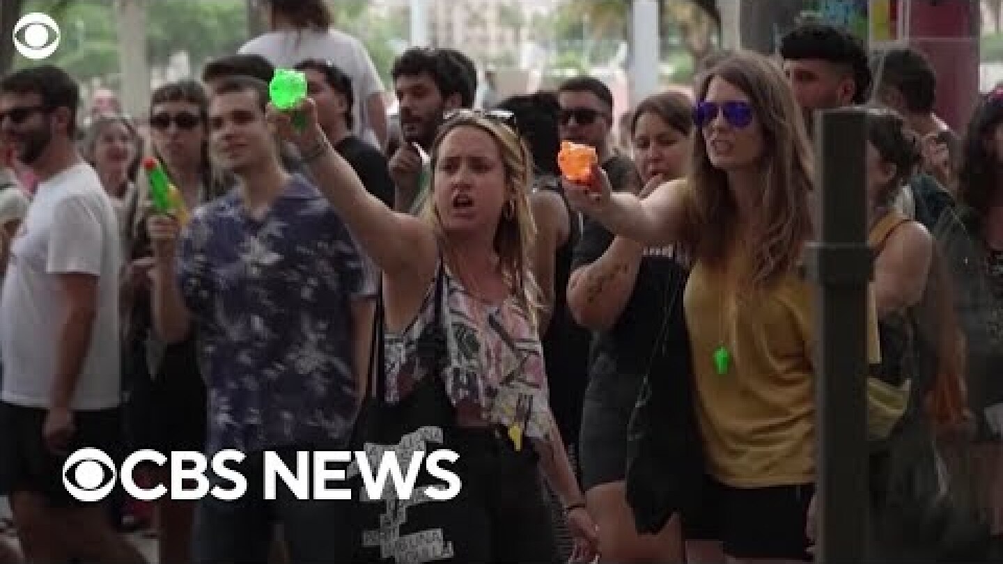 Mass tourism protesters in Barcelona, Spain, spray water at tourists