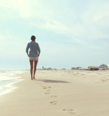 Γυναίκα περπατάει σε παραλία με άμμο